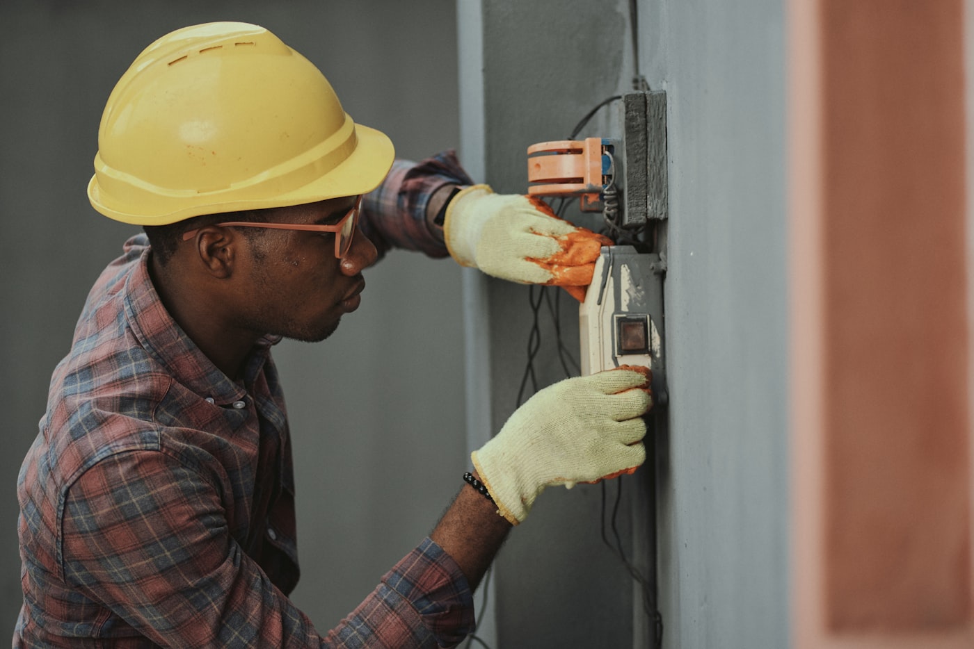 Electrician in a hard hat servicing a building electrical panel